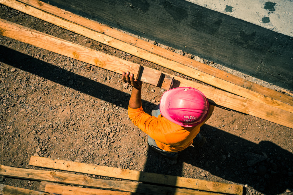 construction site with worker carrying lumber t20 7JOngv